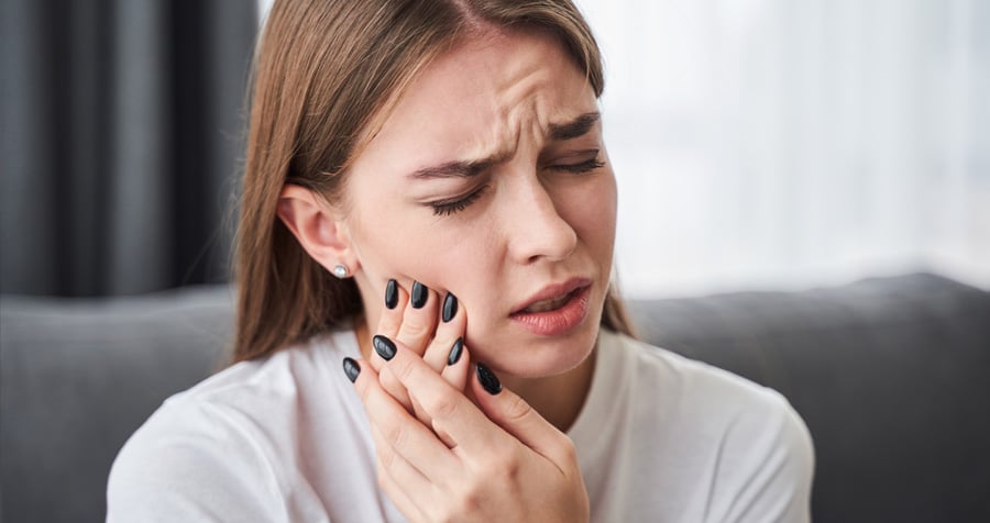 Emergency Dentistry 1 lady touching her cheeks, appearing to experience toothache