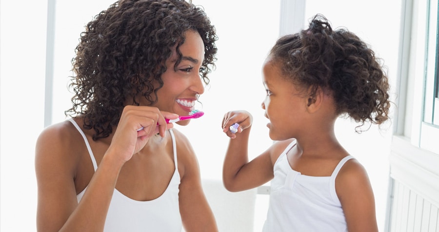 Oral Hygiene 1 mother and daughter smiling while brushing their teeth together